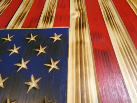 These wooden American flags are locally sourced from pine and finished with environmentally responsible products. The rustic torched finish shows a unique flair making each piece completely special. Stars are carved not merely painted or applied. The proprietary hanger design incorporates a heavy-duty cable system for mounting. The full sized 30" x 16" flags are large enough to be a focal point in any room or man cave.